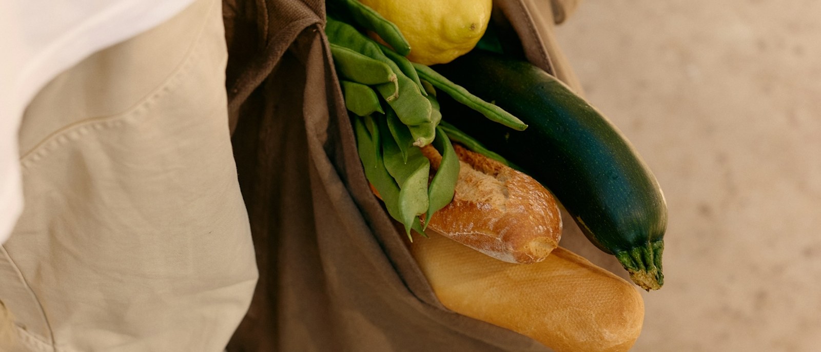 A canvas bag of bread and vegetables, carried home in the sun.