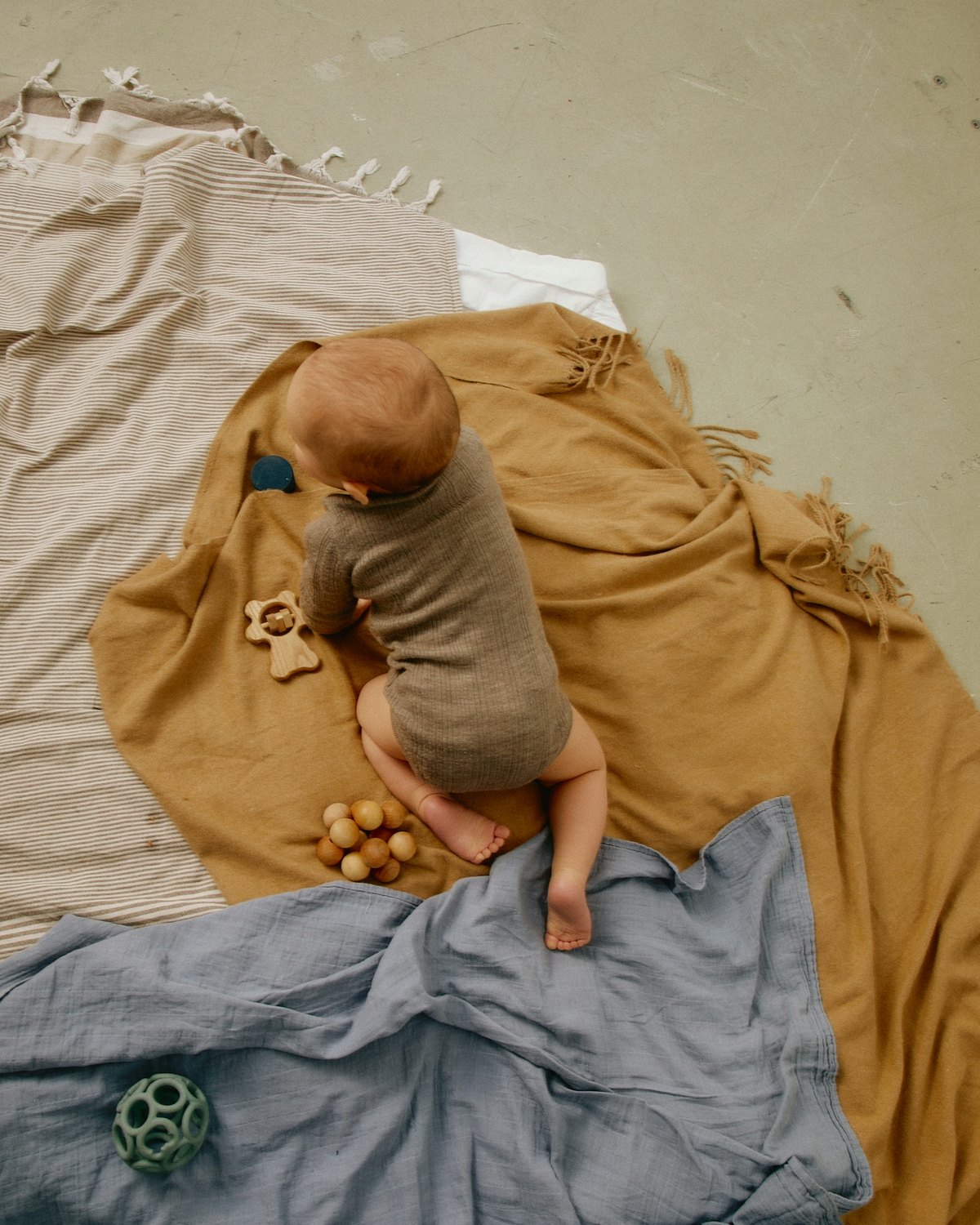 A baby on a blanket on the floor, seen from above.